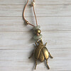 Lange geknoopte ketting met diverse soorten half-edelstenen en hanger in de vorm van een kever