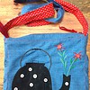 Blauwe tas met theepot en geborduurde bloemen