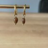Gouden oorbellen met bruine edelsteen.