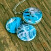 Roestvrij stalen fotomedaillon ketting met drie verschillende verwisselbare voorkanten met close up foto`s van glas in ijsblauw en aqaua blauw. Rvs/roesvrij stalen fotomedaillon. Voor het dicht bij je dragen van je favoriete foto.