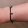 Gevlochten donkergroene armband met gekraakte kralen en goudkleurig blaadje