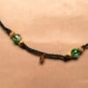 Gevlochten donkergroene armband met gekraakte kralen en goudkleurig blaadje