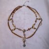 Ketting met blad-hanger, bruin lint en goudkleurige kralen