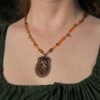 Ketting met bloemenornament in antiek koper en amberkleurige kralen