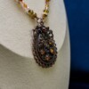 Ketting met bloemenornament in antiek koper en amberkleurige kralen