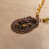 Ketting met bloemenornament in antiek koper en amberkleurige kralen