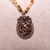 Ketting met bloemenornament in antiek koper en amberkleurige kralen