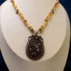 Ketting met bloemenornament in antiek koper en amberkleurige kralen