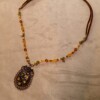 Ketting met bloemenornament in antiek koper en amberkleurige kralen