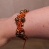 Koperkleurige macramé-armband met goudkleurige kralen