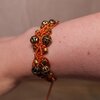 Koperkleurige macramé-armband met goudkleurige kralen