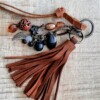 Sleutelhanger, handgemaakt van kralen en leren flos hangen samen aan een sleutelring.