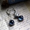 Asymmetrische handgemaakte vogeloorbellen met blauw glas en zilverkleurig koper