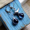 Asymmetrische handgemaakte vogeloorbellen met blauw glas en zilverkleurig koper