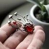 Handgemaakte paddenstoelenbroche met rood glas en zilverkleurig koper
