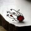 Handgemaakte paddenstoelenbroche met rood glas en zilverkleurig koper
