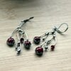 Asymmetrische handgemaakte takoorringen met rood glas en zilverkleurig koper