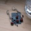 Asymmetrische handgemaakte takoorringen met rood glas en zilverkleurig koper
