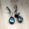 Asymmetrische handgemaakte vogeloorbellen met blauw glas en zwart gepatineerd koper
