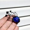 Handgemaakte paddenstoelenbroche met blauw glas en zwart gepatineerd koper