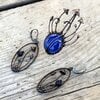 Handgemaakte paddenstoelenbroche met blauw glas en zwart gepatineerd koper