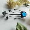 Handgemaakte paddenstoelenbroche met blauw glas en zwart gepatineerd koper