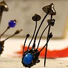 Handgemaakte paddenstoelenbroche met blauw glas en zwart gepatineerd koper