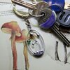 Handgemaakte paddenstoelensleutelhanger met groen glas en zilverkleurig koper