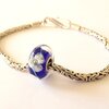 Handgemaakte donkerblauwe lampwork glasbedel met parelmoeren bloemen
