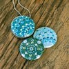 Fotomedaillon ketting met 3 verschillende verwisselbare voorkanten met foto`s van 3 verschillende dotting art kunstwerken.Blauw tinten dotting art.