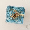 Handgemaakt glazen sieraden schaaltje, blauwe bubbels en steentjes in het glas.
