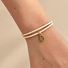 Stijlvol armbandje van crèmekleurig polyurethaan leer met een klein groen bedeltje.