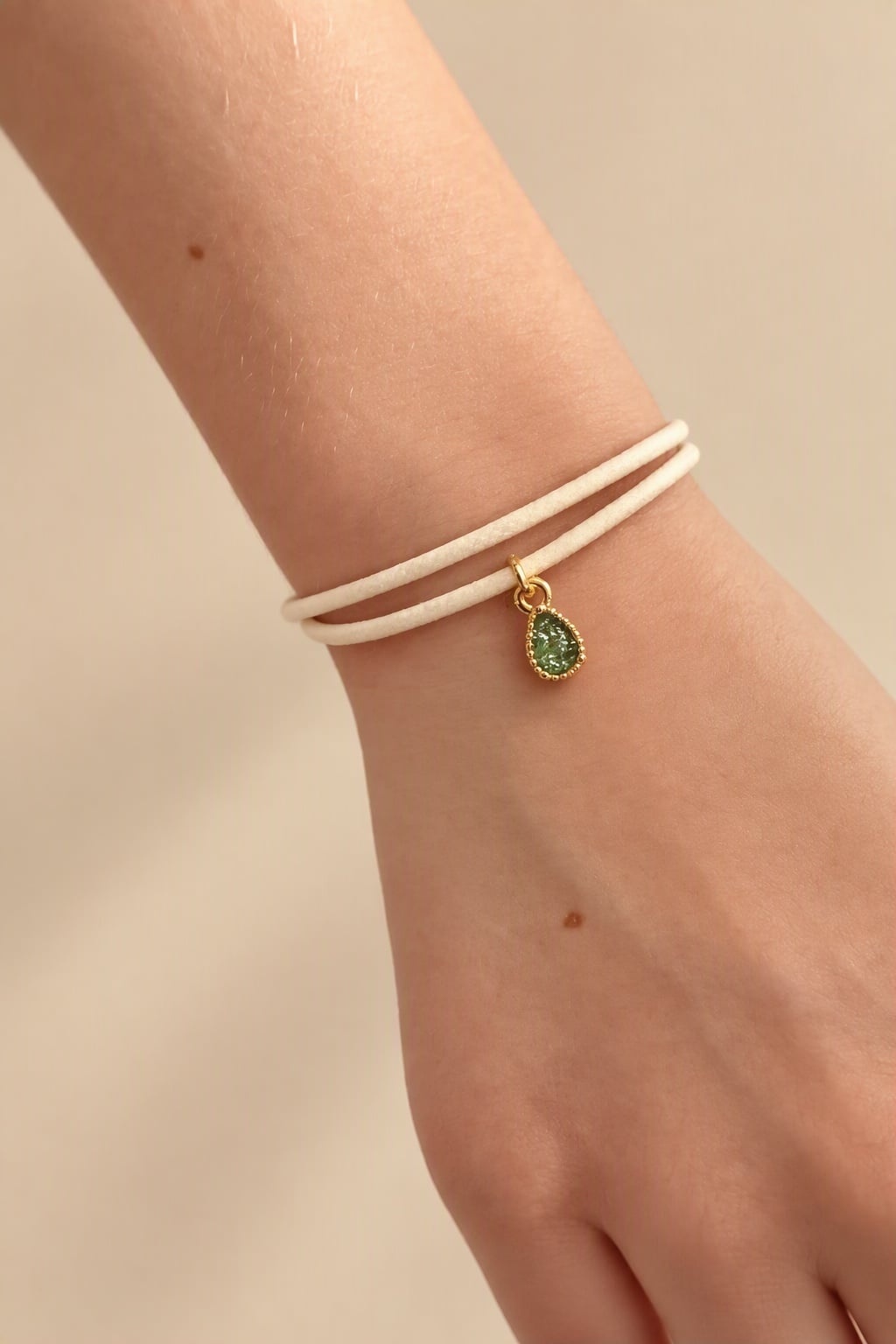 Stijlvol armbandje van crèmekleurig polyurethaan leer met een klein … - 155304 Stijlvol armbandje van crèmekleurig polyurethaan leer met een klein groen bedeltje.