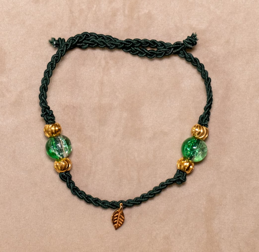 Gevlochten donkergroene armband met gekraakte kralen en goudkleurig b… - 97522 Gevlochten donkergroene armband met gekraakte kralen en goudkleurig blaadje