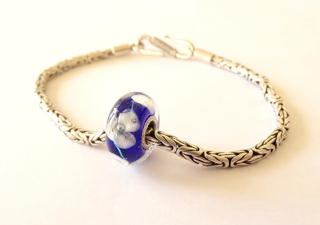 Handgemaakte donkerblauwe lampwork glasbedel met parelmoeren bloemen