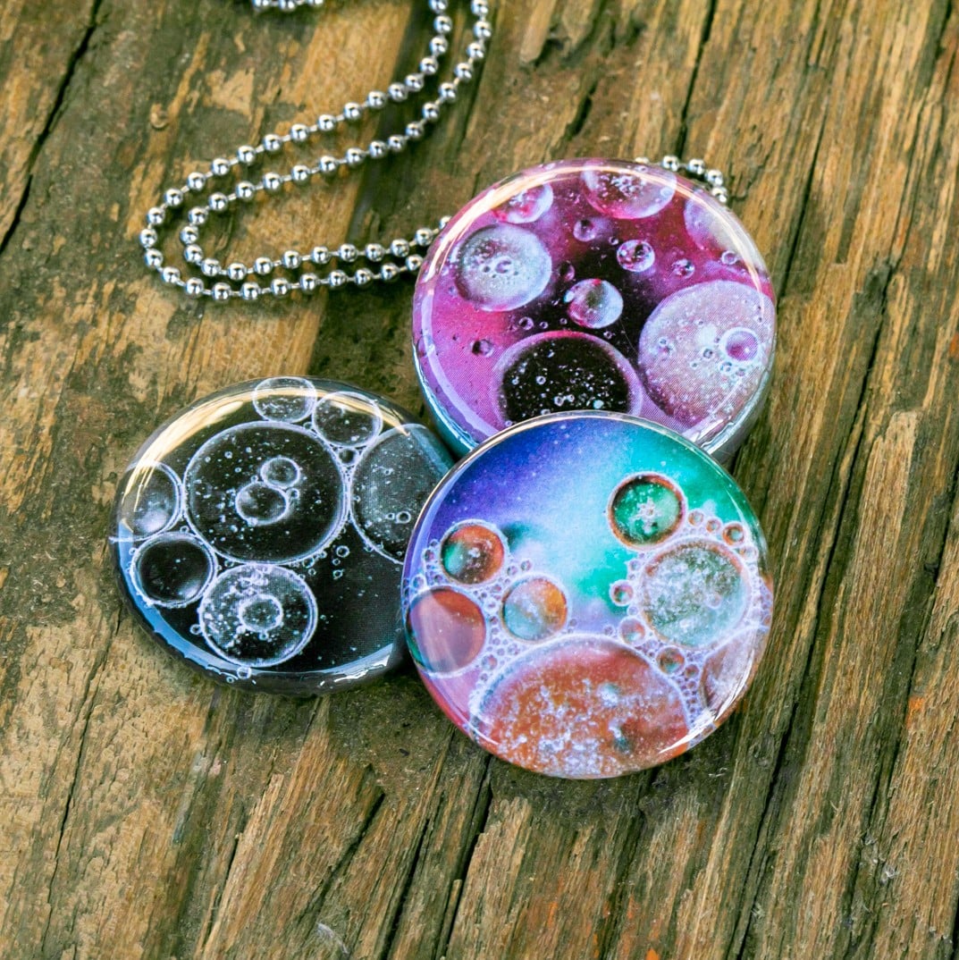 Roestvrij stalen fotomedaillon ketting met drie verschillende verwisselbare voorkanten met close up foto`s van olie druppels in water, in mooie tinten en zwart wit.Rvs/roesvrij stalen fotomedaillon. Voor het dicht bij je dragen van je favoriete foto.