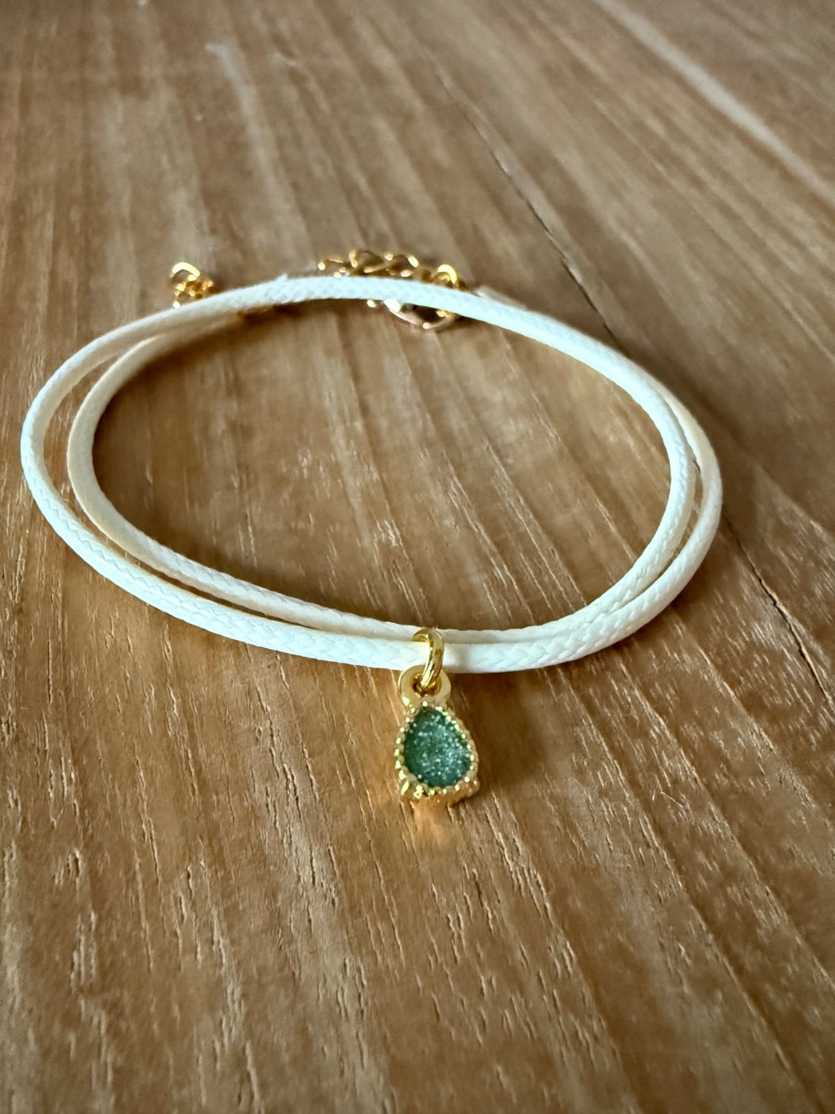 Stijlvol armbandje van crèmekleurig polyurethaan leer met een klein … - 155301 Stijlvol armbandje van crèmekleurig polyurethaan leer met een klein groen bedeltje.
