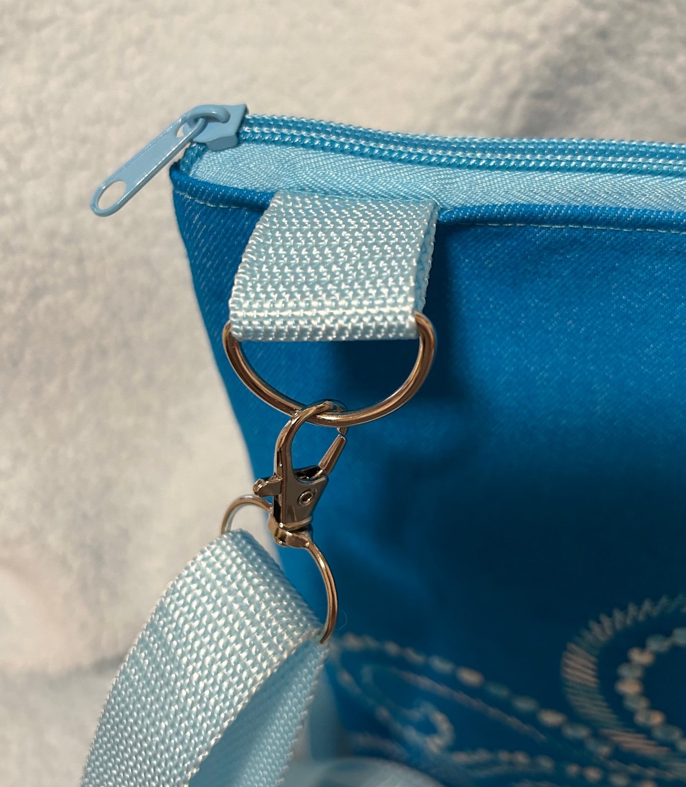 Schoudertas in aqua kleur met geborduurde fantasievogel.