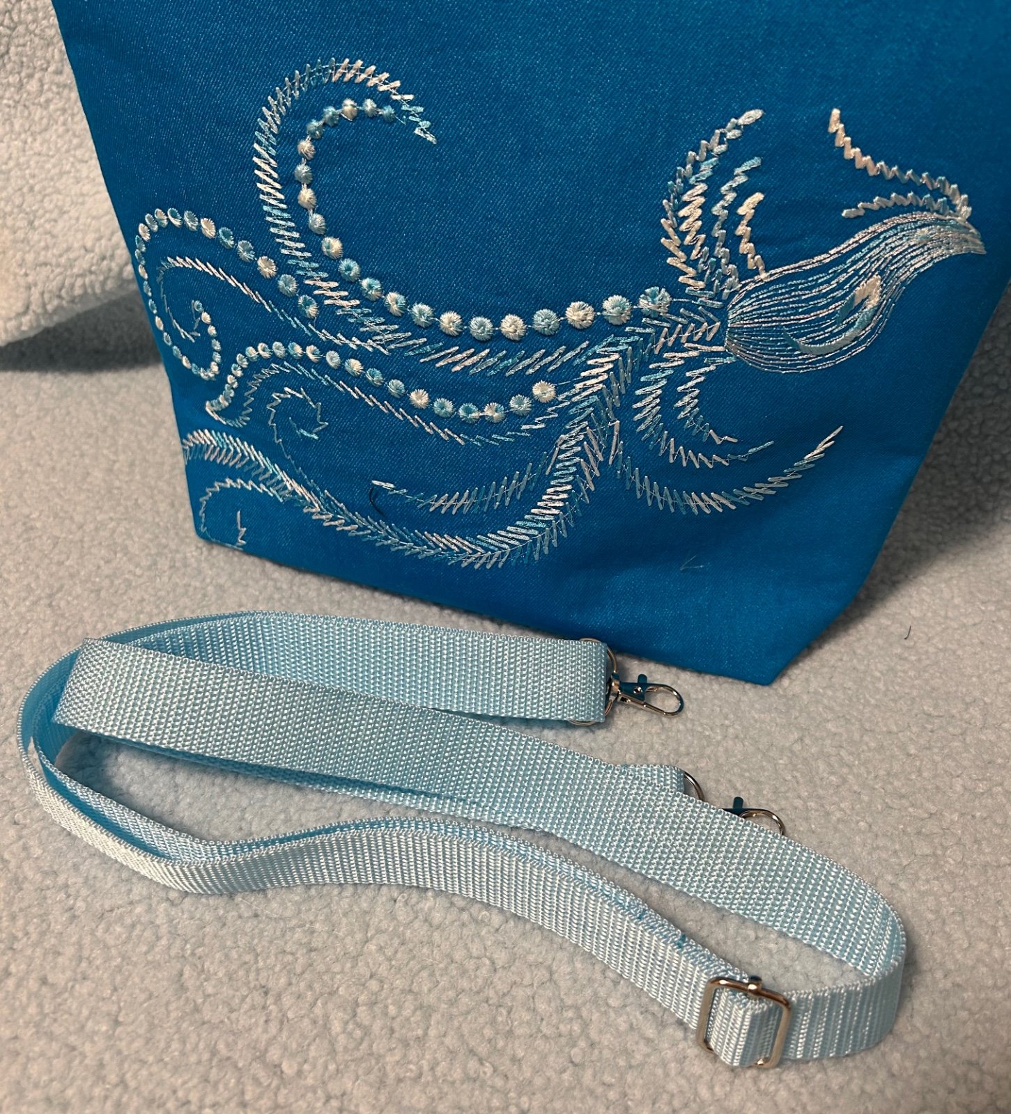 Schoudertas in aqua kleur met geborduurde fantasievogel.