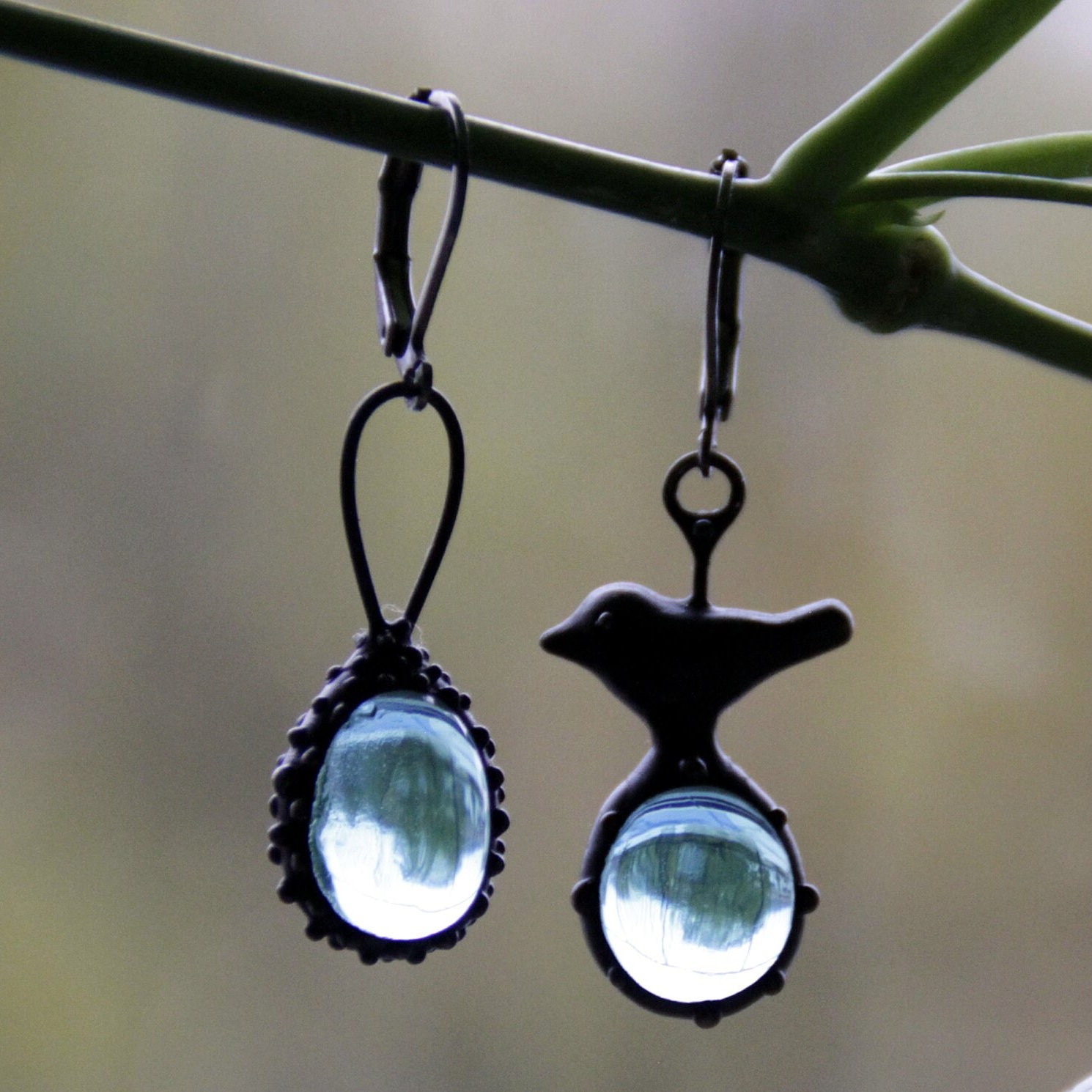 Asymmetrische handgemaakte vogeloorbellen met blauw glas en zwart gepatineerd koper