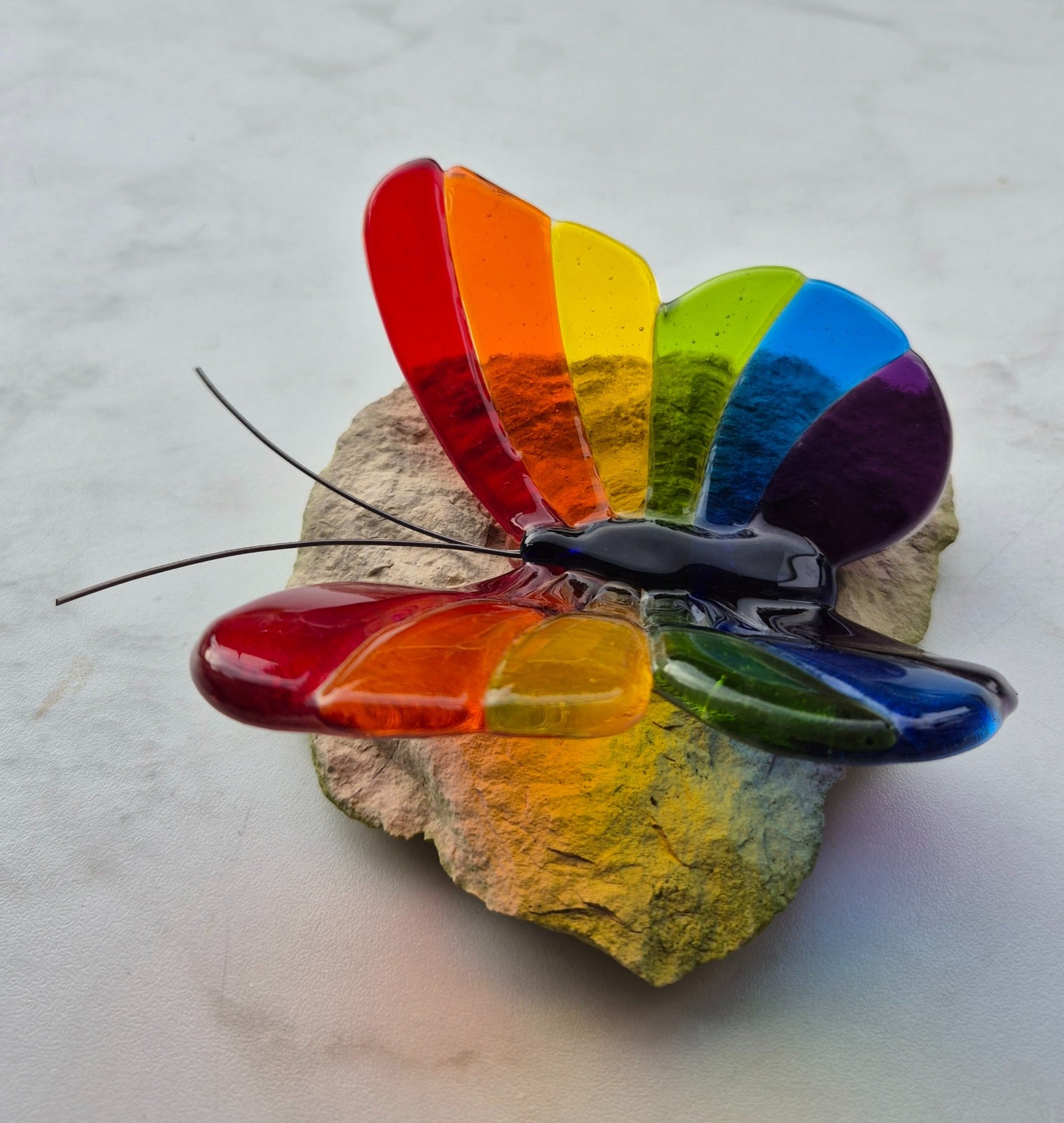 Regenboog vlinder van glas op steen