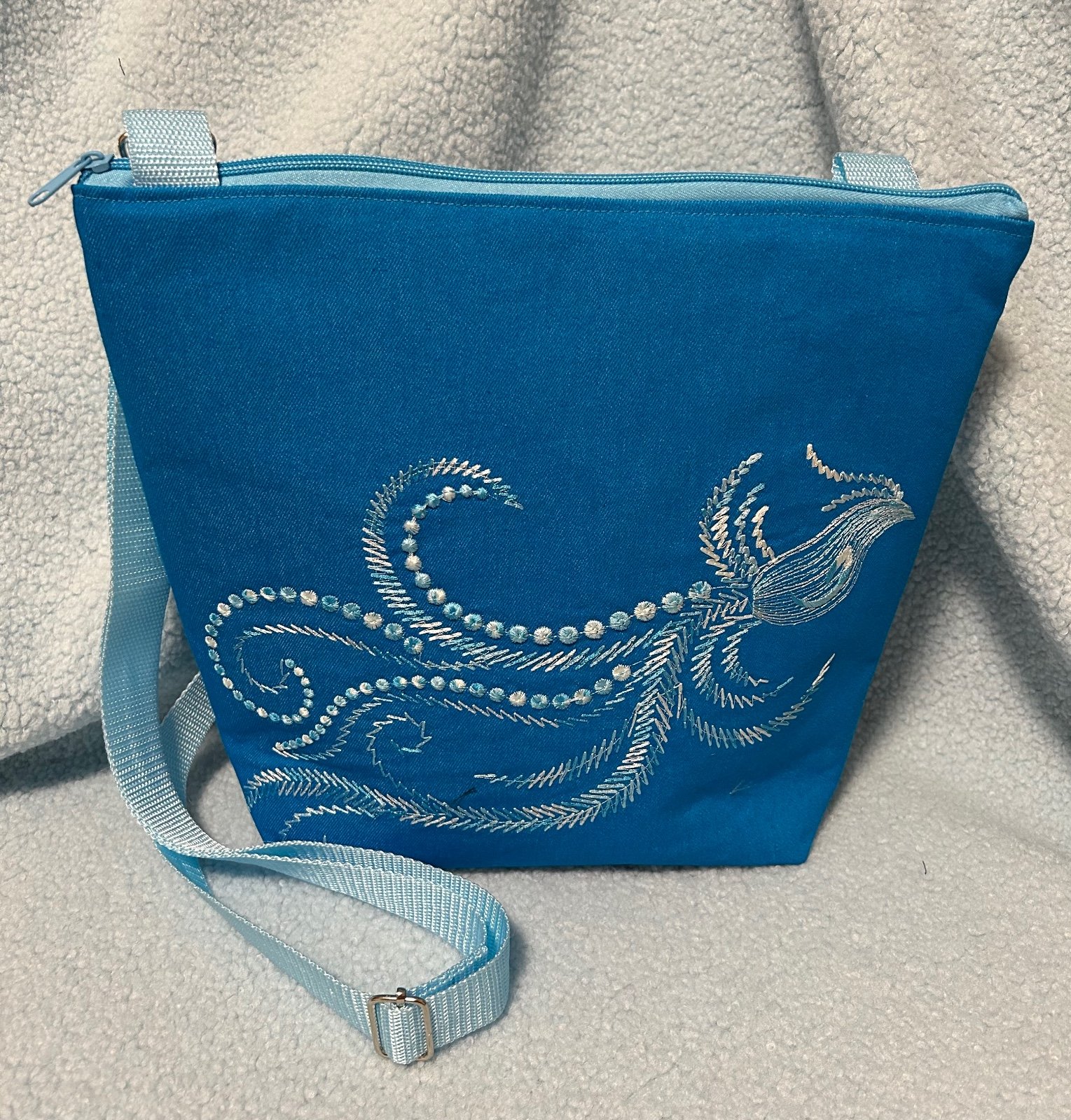 Schoudertas in aqua kleur met geborduurde fantasievogel.