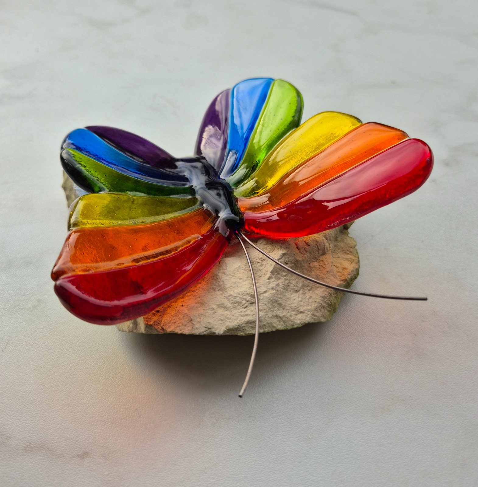 Regenboog vlinder van glas op steen