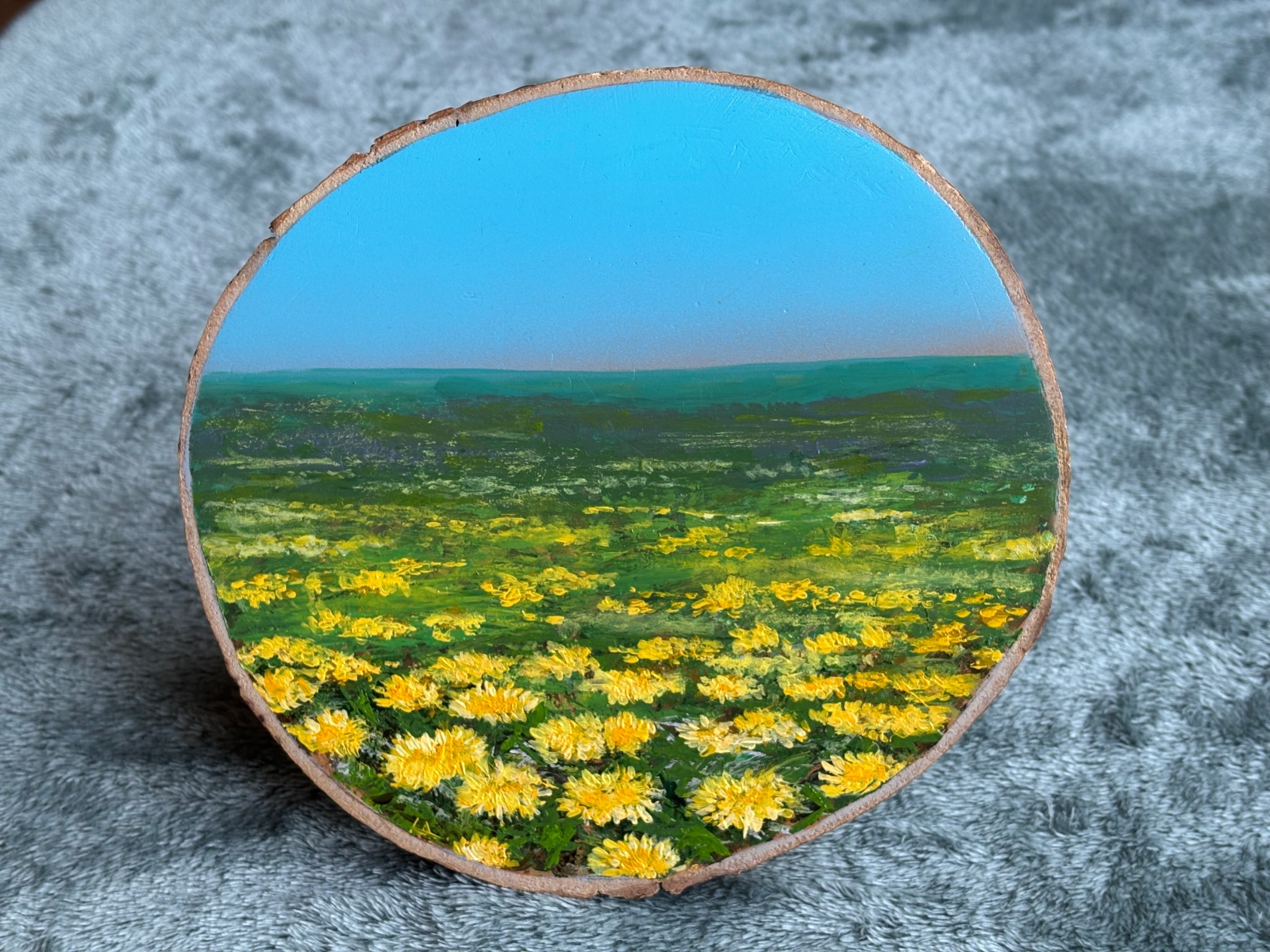 Schilderij op houten schijf met paardenbloemen.