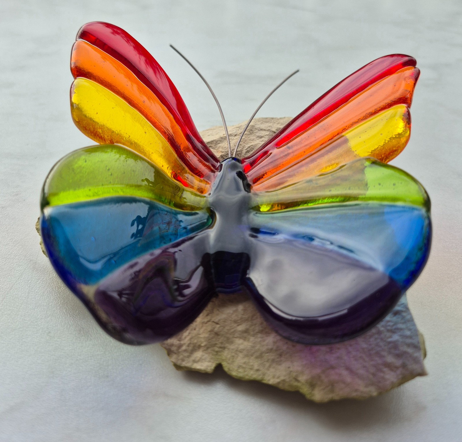 Regenboog vlinder van glas op steen