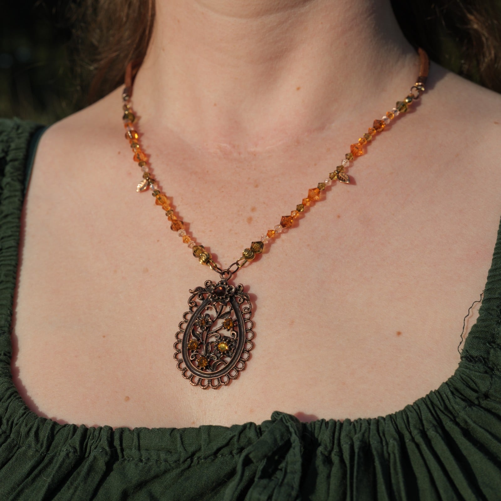 Ketting met bloemenornament in antiek koper en amberkleurige kralen