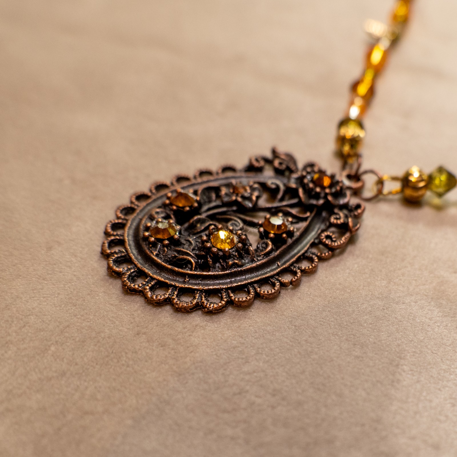 Ketting met bloemenornament in antiek koper en amberkleurige kralen