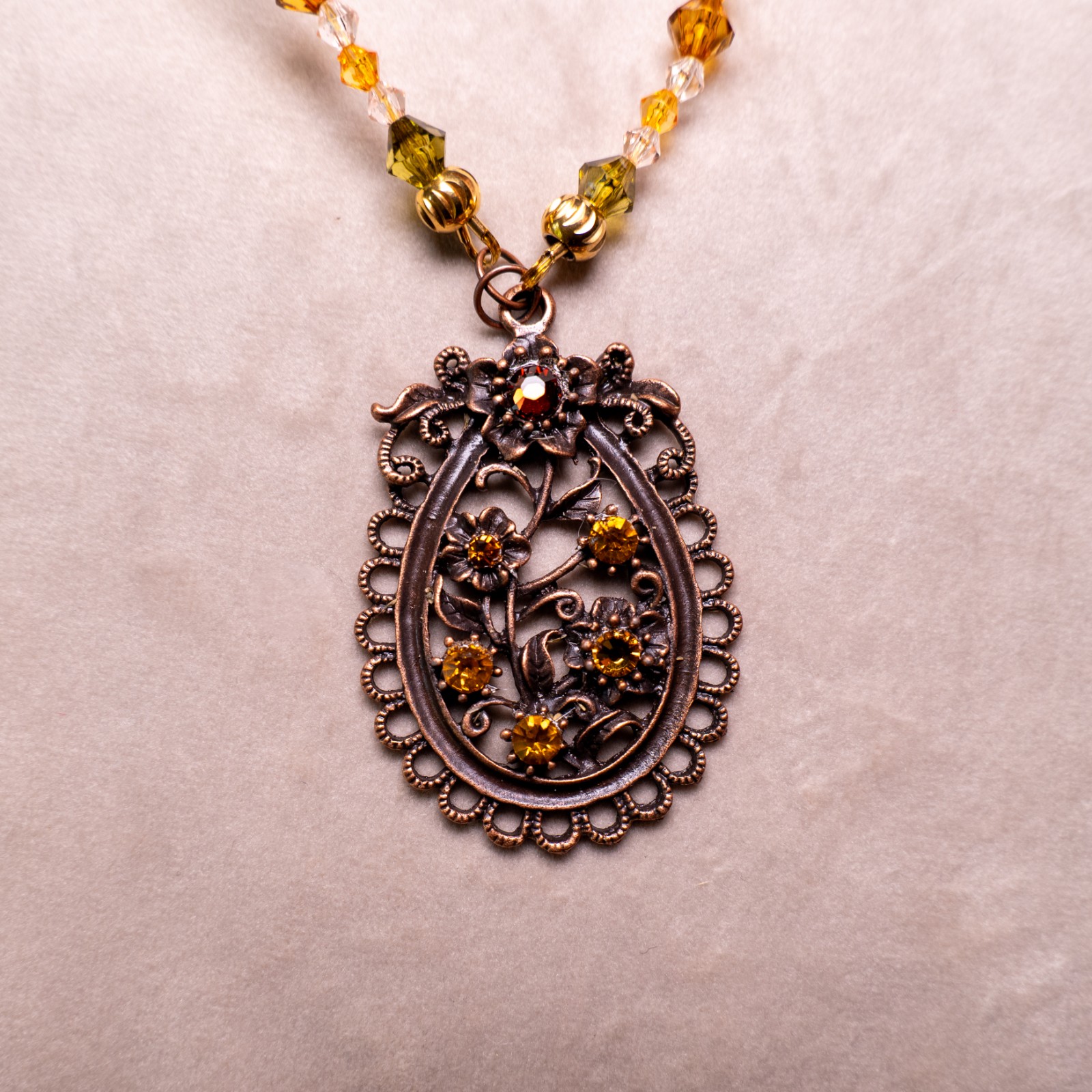 Ketting met bloemenornament in antiek koper en amberkleurige kralen
