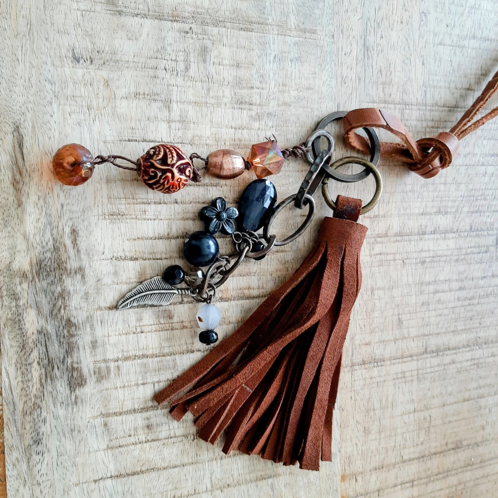 Sleutelhanger, handgemaakt van kralen en leren flos hangen samen aan een sleutelring.