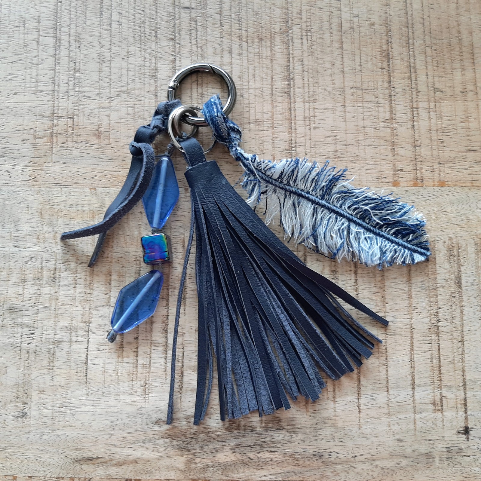 Sleutelhanger handgemaakt met leren kwast, kralen en denim veer. Ook te gebruiken als Bagcharm, tassenhanger